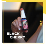 Hand holding a small blue Scent Bomb Black Cherry spray bottle over a blurred background with text overlay