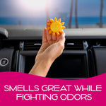 Hand holding a small yellow sun-shaped vent air freshener inside a car above the dash