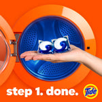 Hand holding two blue-and-white Tide-style detergent pods in front of an orange washing machine drum with "step 1. done." text