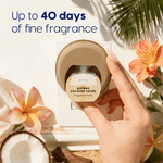 Close-up of hand installing a golden coconut sands refill into a wall-mounted Scent Theory diffuser with decorative flowers and coconut halves