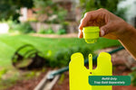 Close-up of a hand installing a green lure cartridge into the top of a fluorescent yellow trap in a backyard setting