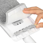 Close-up of a hand peeling back a gray microfiber mop pad to reveal the mop head attachment and locking tabs