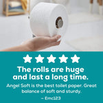 Hand placing a large embossed Angel Soft toilet paper roll onto a holder with a testimonial overlay below