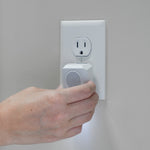Hand plugging a white Victor PestChaser device into a wall outlet with a small illuminated nightlight