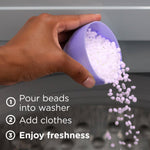 Hand pouring small white scent beads from a purple measuring cup into a washing machine with usage steps text