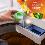 hand pouring liquid fabric softener from a green cap into a washing machine softener dispenser with tropical flowers and text in the corner