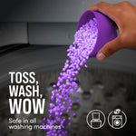 Hand pouring purple scent beads from a measuring cup into a washing machine with 'TOSS, WASH, WOW' text