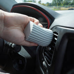 Hand pressing a gray ribbed Damp Duster sponge into a car air vent to remove dust.