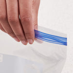 Close-up of a hand pressing the blue double-zipper seal on a clear freezer bag to show the double zipper closure.