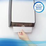 Hand pulling a Scott towel from a wall-mounted dispenser with a coordinating Slimfold dispenser callout badge