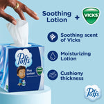 Hand pulling a tissue from a Puffs Plus Lotion cube box with Vicks logo and benefit icons on a light blue background.