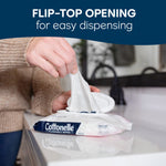 Hand pulling a wipe from a Cottonelle flip-top pack on a glossy bathroom countertop