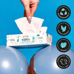 Hand pulling a wipe from a Poo-Pourri flushable wipes box positioned between two blue balloons with certification icons at right