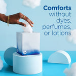 Hand reaching for tissue from a Puffs Ultra Soft cube on a pedestal with text about comforts without dyes or perfumes