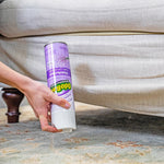Hand reaching under a sofa holding an OdoBan lavender disinfectant aerosol can near a rug