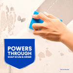 Hand scrubbing a soapy surface with a blue sponge and a 'Powers Through Soap Scum & Grime' shield graphic