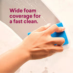 Hand scrubbing a foamed bathroom surface with a blue sponge alongside text about wide foam coverage