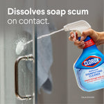 Hand spraying Clorox Bathroom Disinfecting Cleaner at soap scum on a shower glass door with text "Dissolves soap scum on contact."