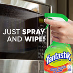 Hand holding a Fantastik spray bottle in front of a microwave with text 'Just spray and wipe!' and product label visible