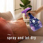 Hand holding and spraying a Febreze Fabric Calm bottle toward couch pillows with overlaid text "spray and let dry"
