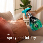 Hand holding a Febreze Unstopables Touch fabric spray above a couch cushion with overlay text spray and let dry