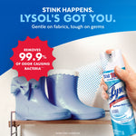 Hand holding a Lysol spray can toward a pair of blue rubber boots with a red badge claiming removal of 99.9% of odor causing bacteria