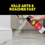 Hand spraying a Raid Ant & Roach lavender aerosol along a baseboard toward ants on tile floor