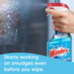 Close-up of a hand holding a Windex spray bottle and misting a glass surface, with partial product label visible and text overlay at bottom.