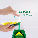 Hand pressing an EZ-pump dispensing green Palmolive liquid onto a yellow-and-green scouring sponge against tiled background