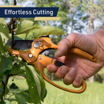 Close-up of a hand gripping orange ratchet pruning shears cutting a branch with overlay text 'Effortless Cutting'