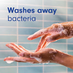 Foaming soapy hands being rinsed in front of tiled background with text Washes away bacteria