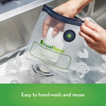 Hands holding a wet FoodSaver reusable zipper bag over a sink, showing valve, logo and writable label lines
