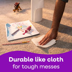 Hand using a Viva paper towel to clean paint and marker mess from a carpet beside a roll upright