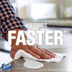 Hand wiping a countertop with a Scott paper towel showing absorbent cleaning action and large absorbs faster text