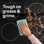 Hand wiping a stovetop with a cloth showing greasy mess being cleaned and text ‘Tough on grease & grime.’