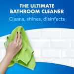 Hand wiping glossy white subway tile with a green cloth under headline promoting the ultimate bathroom cleaner