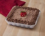 Baked frosted chocolate cake presented inside an aluminum square pan on a wood surface with a red cloth in the background