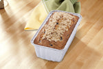 Baked loaf in a disposable Handi-Foil aluminum loaf pan on a wooden surface with a cloth napkin