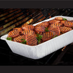 Extra-deep aluminum foil pan on a grill filled with grilled meat pieces and garnishing