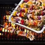 Aluminum Handi-Foil pan filled with colorful shrimp and vegetable skewers cooking on a grill over flames