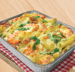 Rectangular aluminum baking pan filled with a cheesy pasta bake garnished with herbs, placed on a wood surface