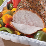 Close-up of a sliced roast with colorful bell peppers served in a disposable aluminum foil roaster pan