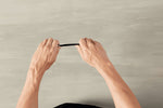 Pair of hands bending a black disposable plastic knife against a neutral background, demonstrating flexibility