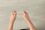 Two hands bending a white disposable plastic spoon horizontally to demonstrate flexibility