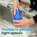 Hands cleaning inside a glass using a blue flexible scrub sponge over a kitchen sink
