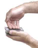 Two hands holding a small gray de-greaser brush, showing top grip and black bristles