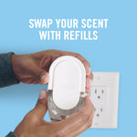 Hands holding a Febreze plug-in device near a wall outlet with caption 'SWAP YOUR SCENT WITH REFILLS'