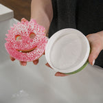 Hands holding an open Scrub Daddy PowerPaste tub showing white paste and a pink Scrub Mommy sponge applicator