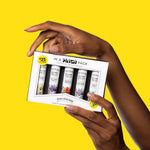 Hands holding a boxed Poo-Pourri In A Pinch pack showing five Before-You-Go travel sprays against a yellow background