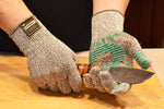 Hands wearing gray knit gloves with teal grip holding and sharpening a large kitchen knife